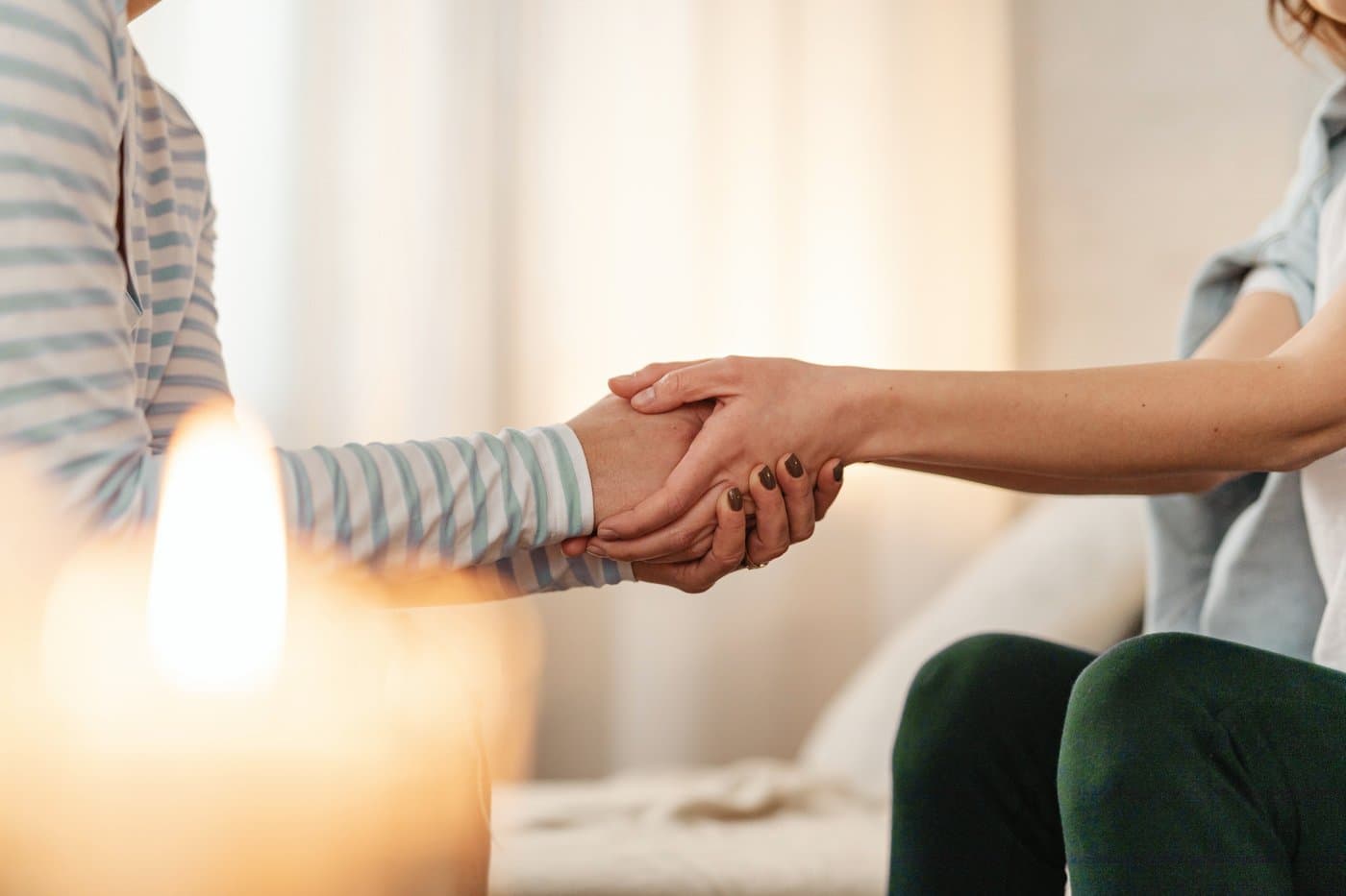 Two women holding hands in a supportive gesture
