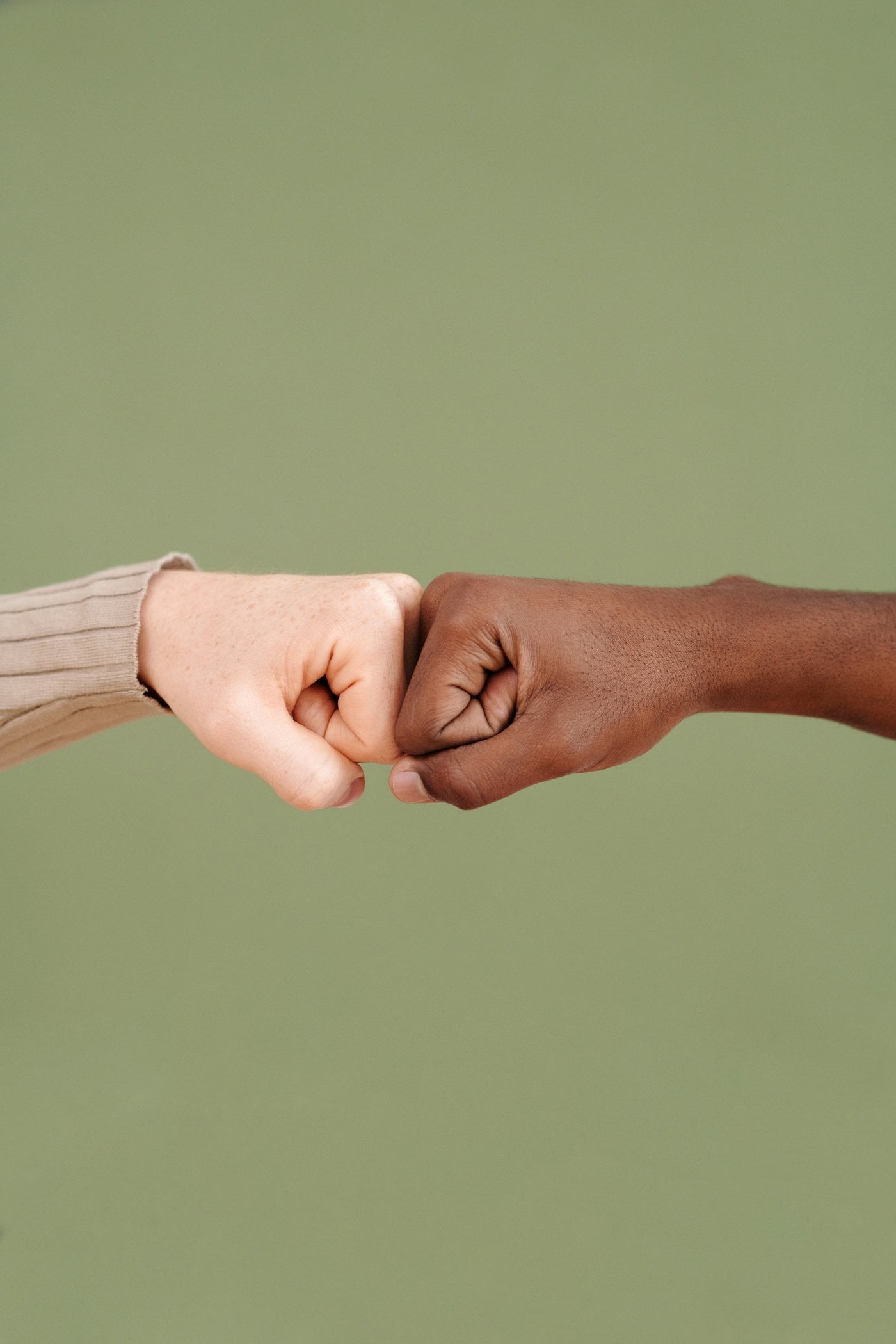 Two hands of different skin tones fist bumping, representing cultural diversity and unity
